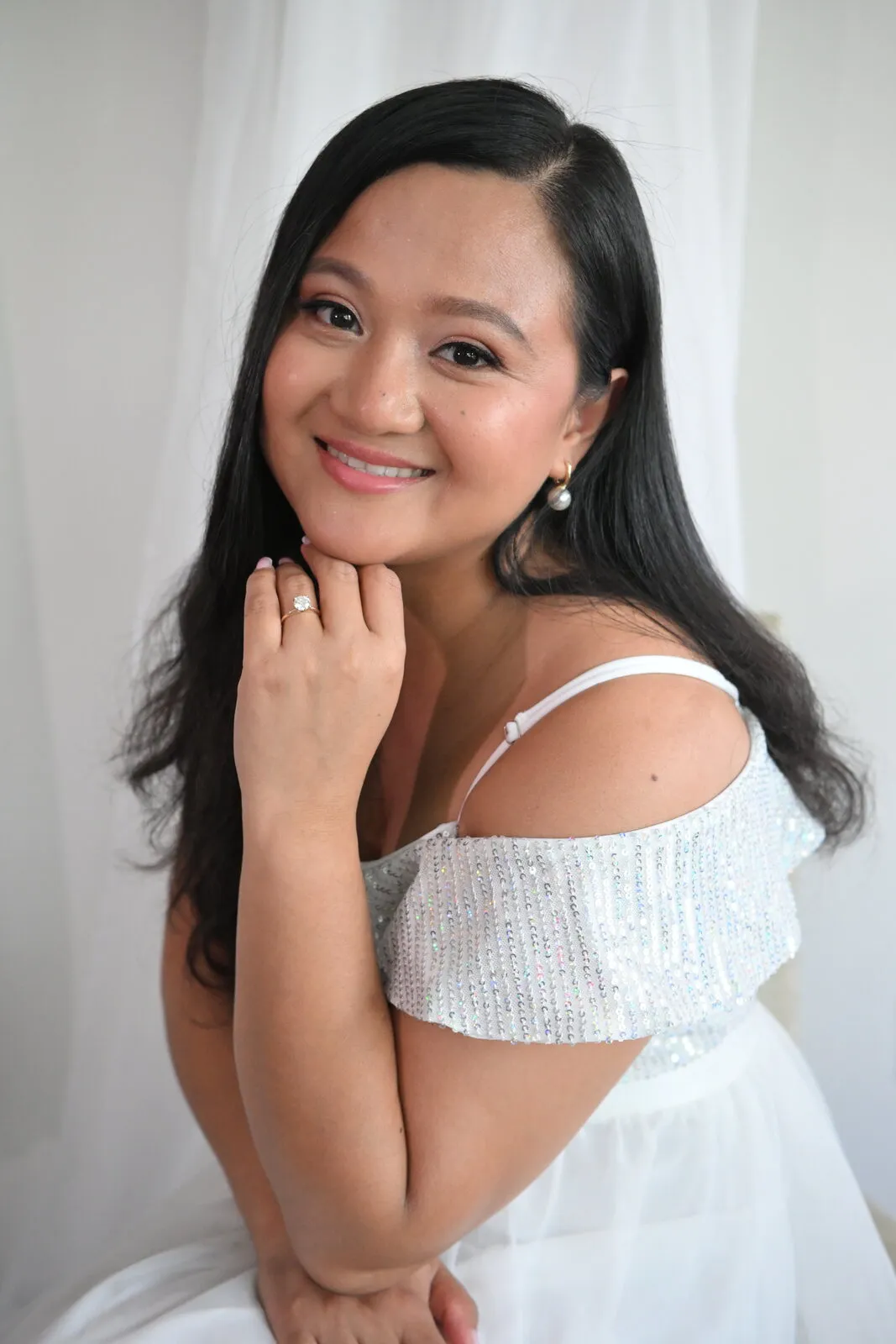 Bride in an off-shoulder dress resting her chin on her hand