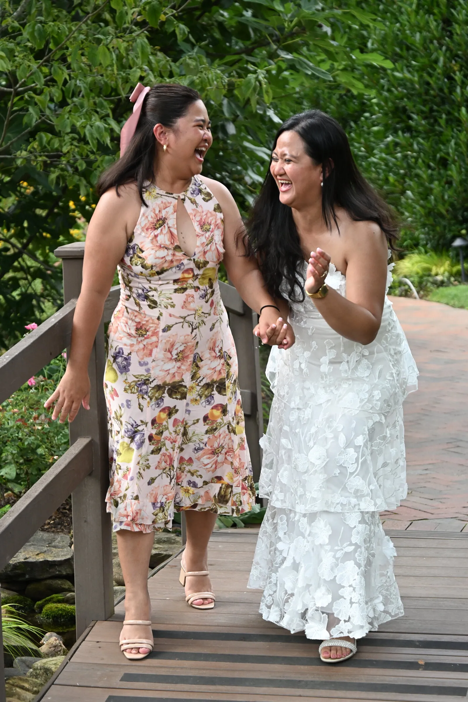 Bride laughing with a guest on a garden bridge